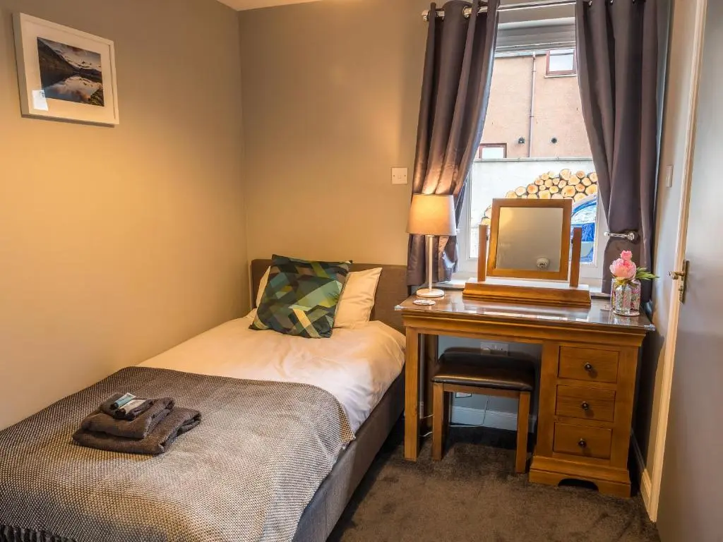 a bedroom with a bed and a mirror and a desk at The Birches in Dingwall