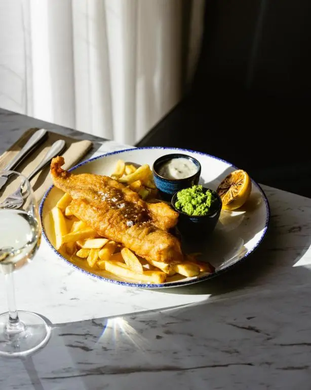 a plate of food with fish and fries on a table at Leonardo Hotel and Conference Venue Aberdeen Airport in Dyce