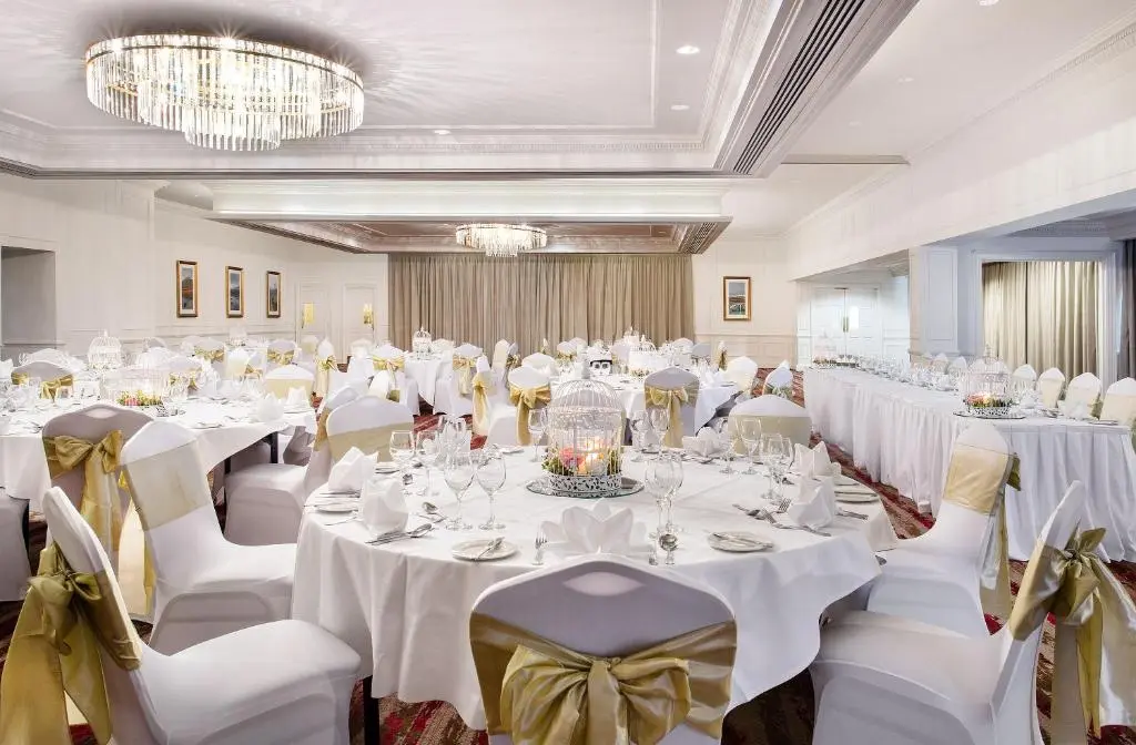 a banquet hall with white tables and chairs and chandeliers at Leonardo Hotel and Conference Venue Aberdeen Airport in Dyce