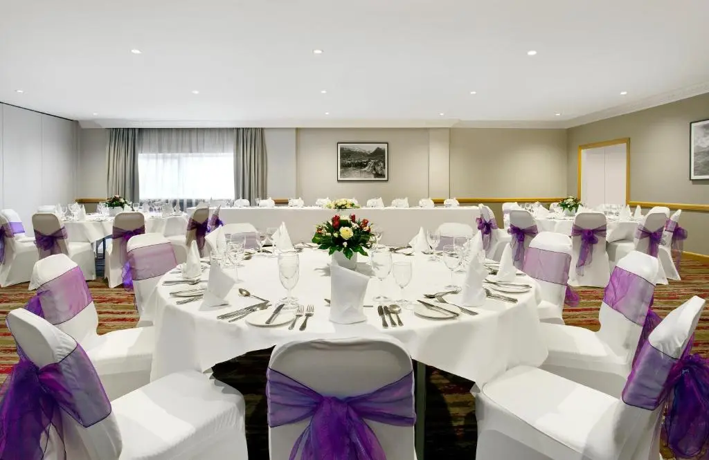 a banquet hall with white tables and purple chairs at Leonardo Hotel Inverness in Inverness