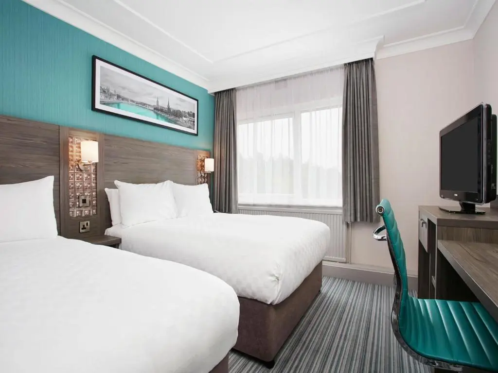 a hotel room with two beds and a flat screen tv at Leonardo Hotel Inverness in Inverness