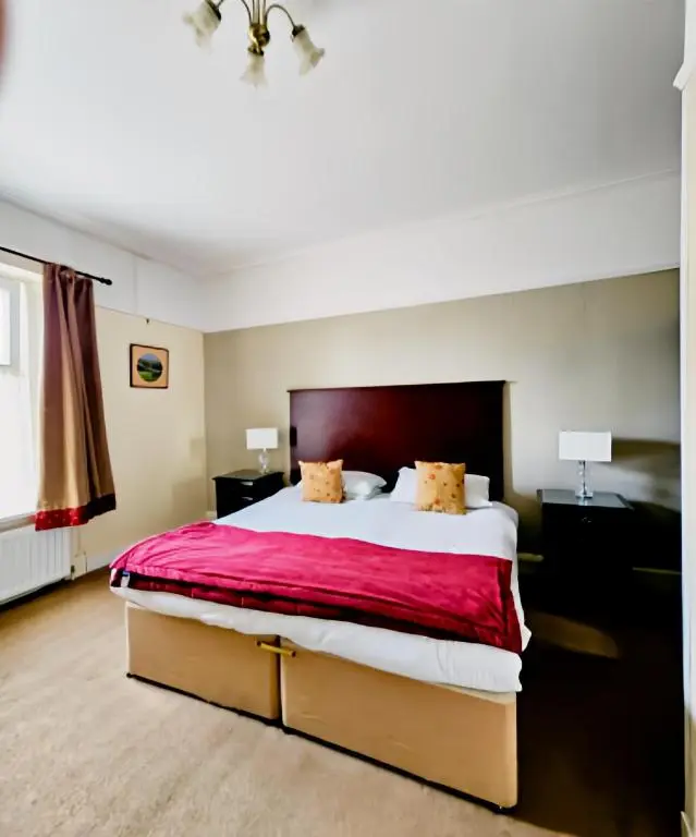 a bedroom with a large bed with a red blanket at The Station Hotel in Portsoy