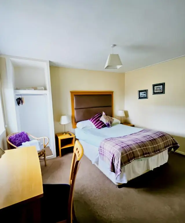 a bedroom with a large bed and a chair at The Station Hotel in Portsoy