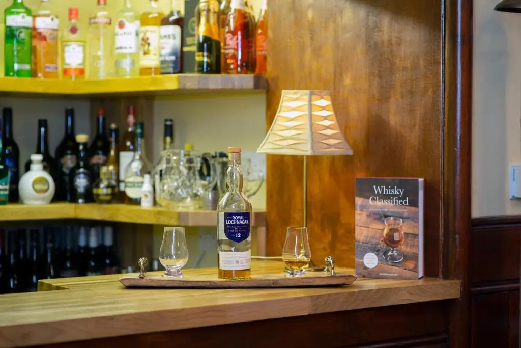 a bottle of wine and two glasses on a bar at The Auld Kirk in Ballater