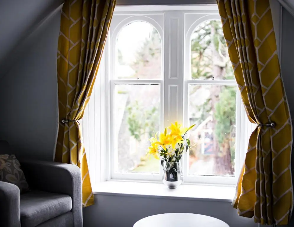 a vase with yellow flowers sitting on a window sill at McInnes House rooms with breakfast in Kingussie