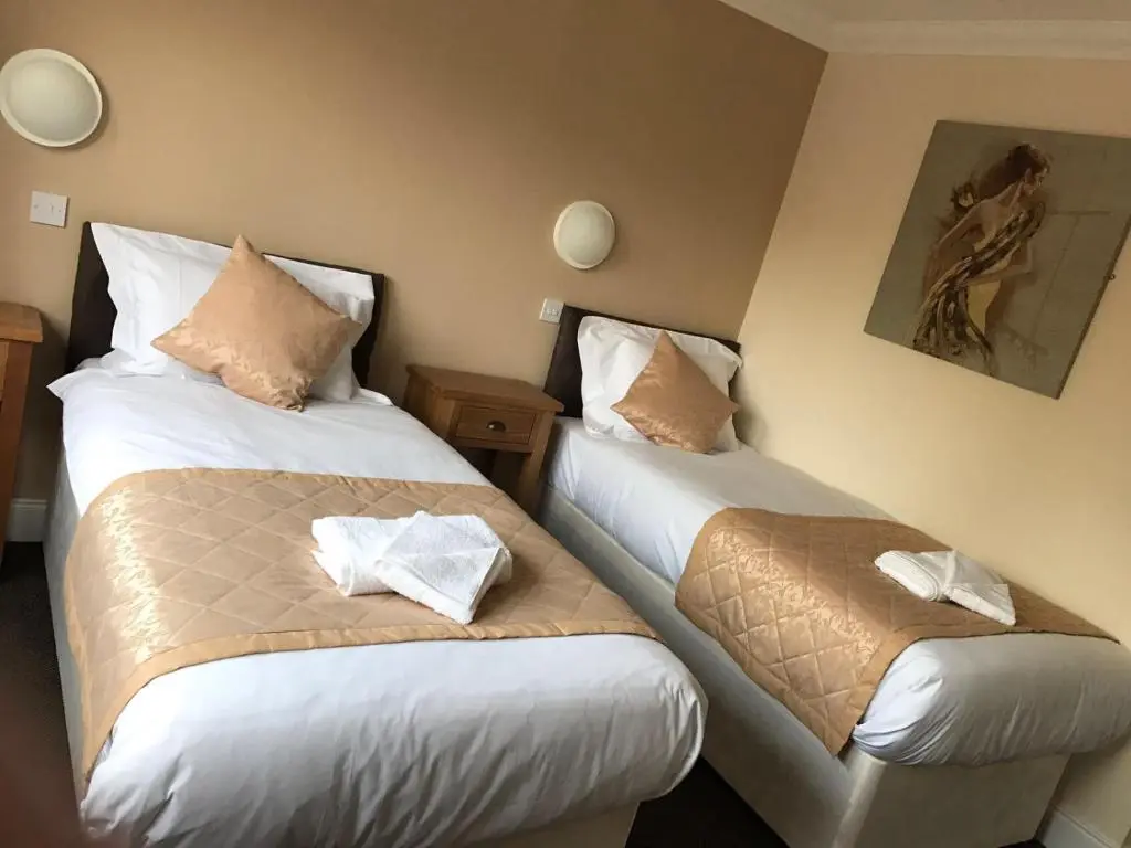 two beds in a hotel room with towels at The Waverley Inn in Dingwall