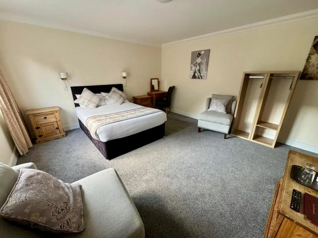 a hotel room with a bed and a chair at The Waverley Inn in Dingwall