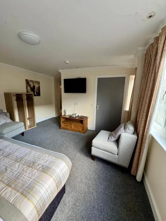a bedroom with a bed and a chair and a television at The Waverley Inn in Dingwall