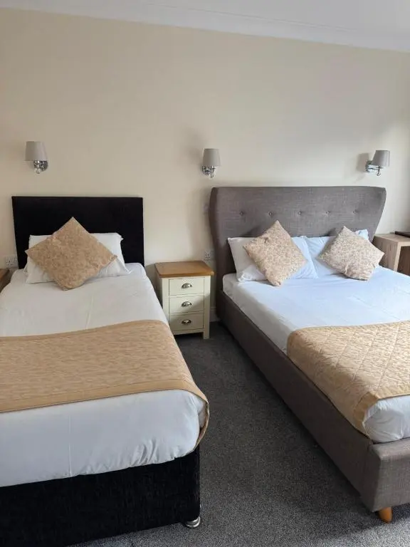 a hotel room with two beds and a night stand at The Waverley Inn in Dingwall