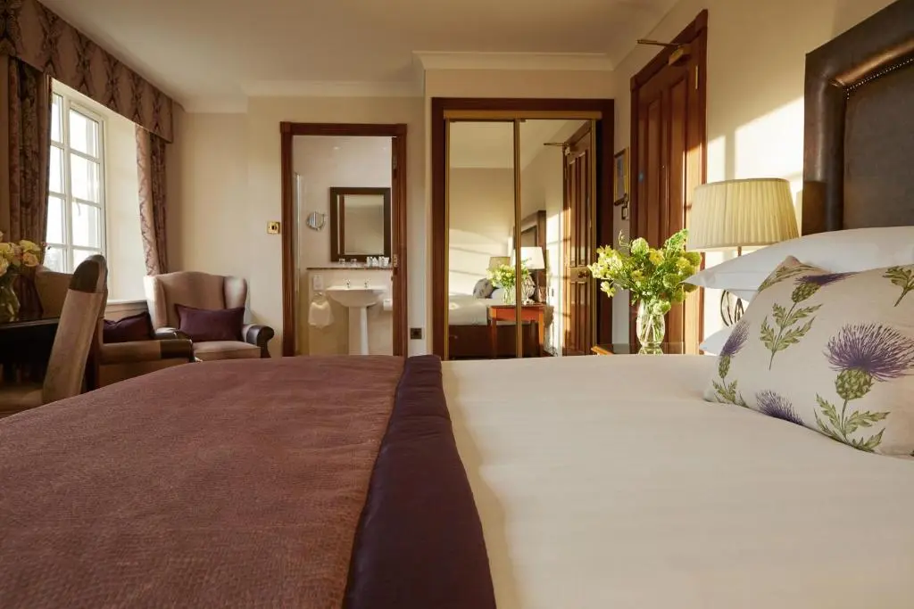 a bedroom with a large bed and a bathroom at Macdonald Drumossie Hotel Inverness in Inverness
