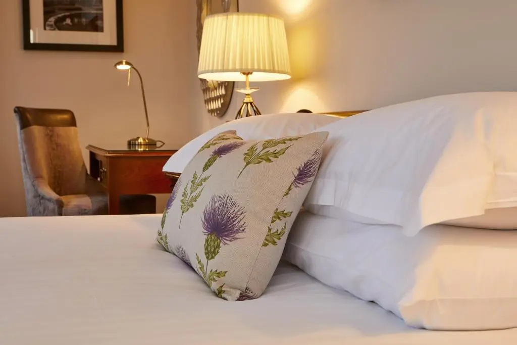 a bed with white sheets and a pillow on it at Macdonald Drumossie Hotel Inverness in Inverness