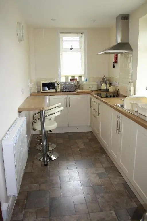 a kitchen with white cabinets and a counter top at Mary's Apartment in Rothes