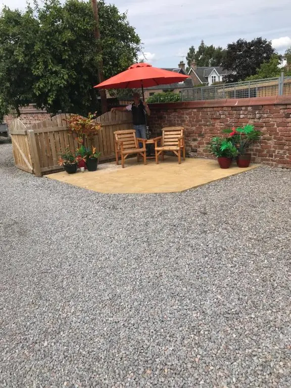 a patio with a table and chairs and an umbrella at Garfield Guesthouse in Dingwall