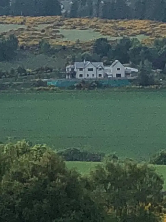 a large house in the middle of a green field at Doura Lodge in Inverness
