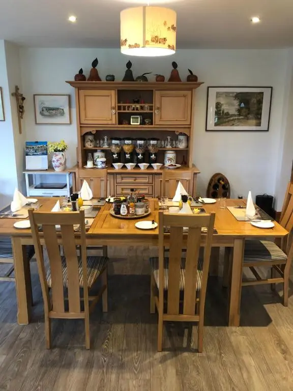a dining room with a wooden table and chairs at Doura Lodge in Inverness
