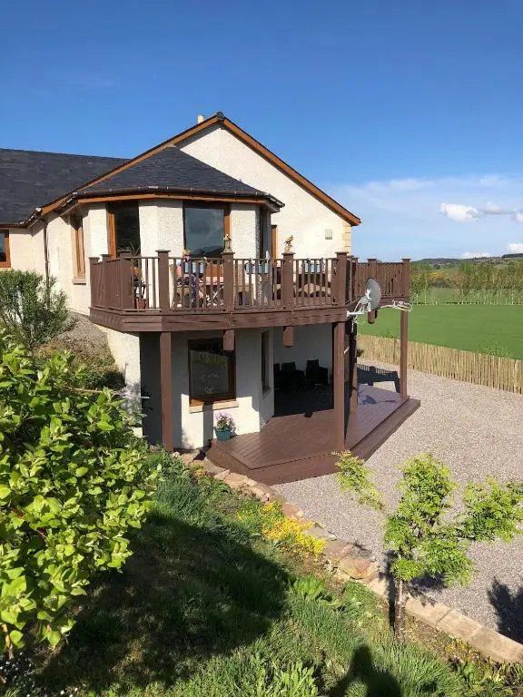 a house with a large deck on top of it at Doura Lodge in Inverness