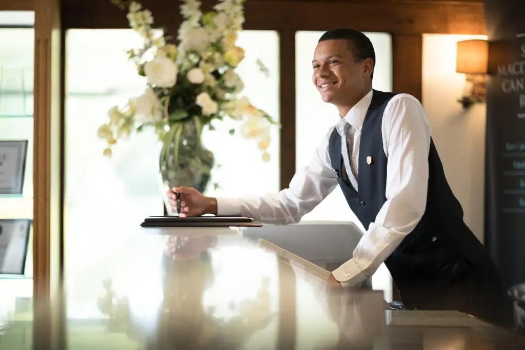 a man standing at a desk with a laptop at Macdonald Highlands Hotel at Macdonald Aviemore Resort in Aviemore