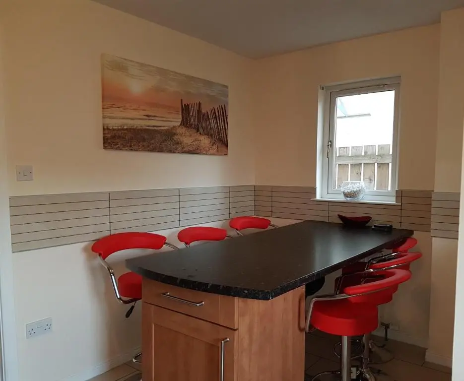 a kitchen with a black counter and red stools at Jane's Villa Free Parking in Inverness