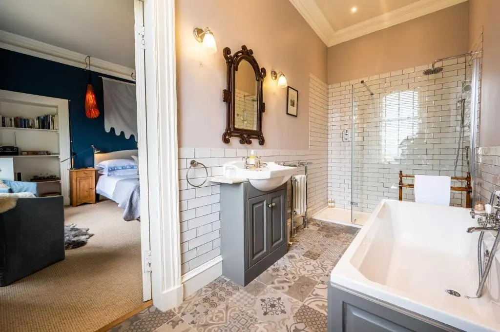 a bathroom with a tub and a sink and a bed at Washington House in Nairn