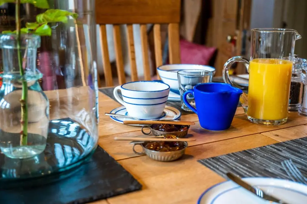 a wooden table with plates and cups and orange juice at Washington House in Nairn