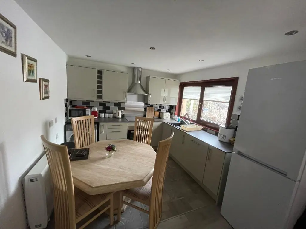 a kitchen with a table and chairs and a refrigerator at Coppice Cottage in Grantown on Spey