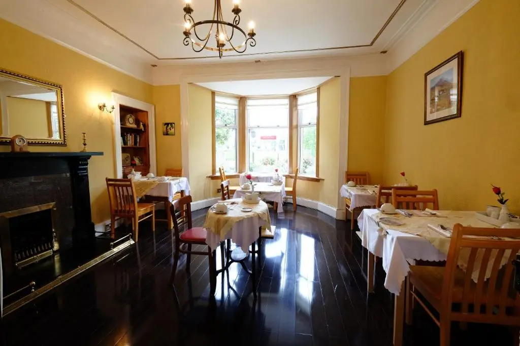 a dining room with tables and chairs and a chandelier at Talisker Guest House in Inverness