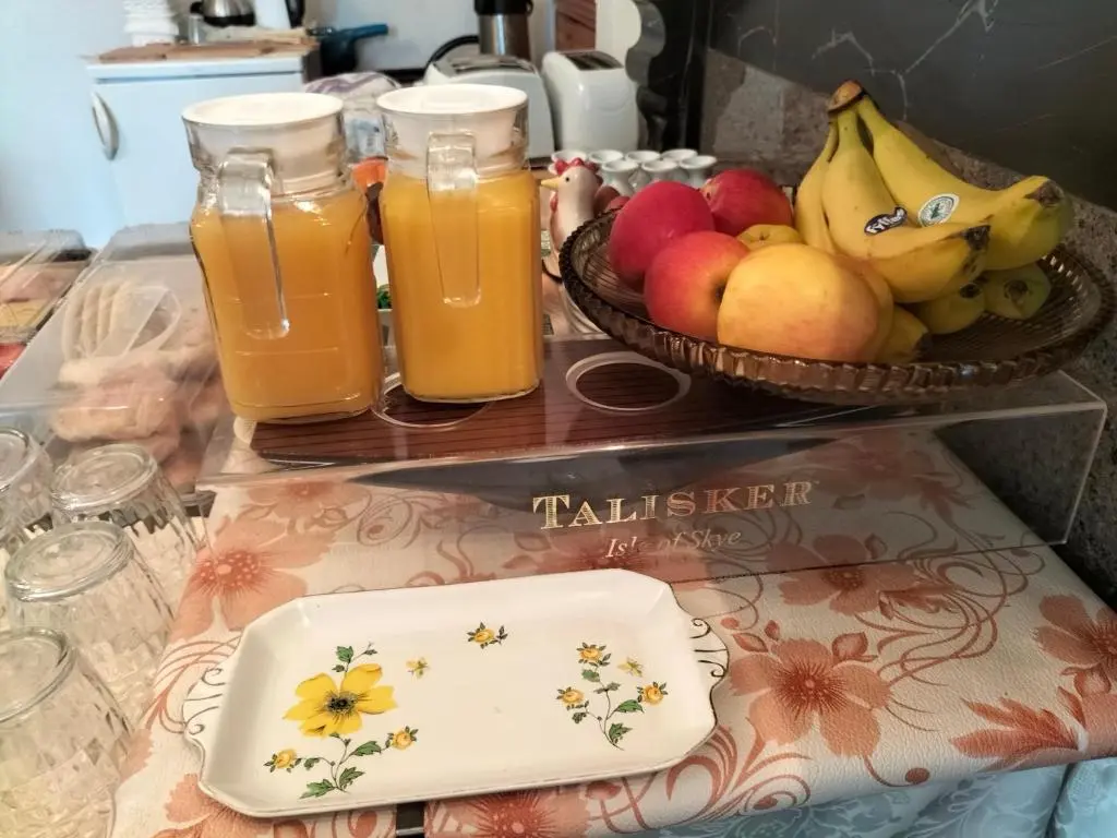 a table with two glasses of juice and a bowl of fruit at Talisker Guest House in Inverness