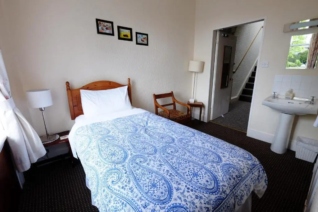 a bedroom with a blue and white bed and a sink at Talisker Guest House in Inverness