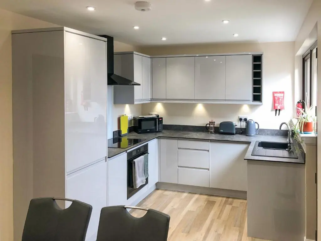 a kitchen with white cabinets and black appliances at Firth View in Garmouth