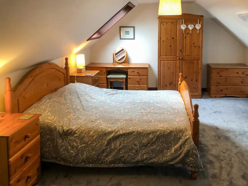 a bedroom with a bed with a dresser and a desk at Firth View in Garmouth