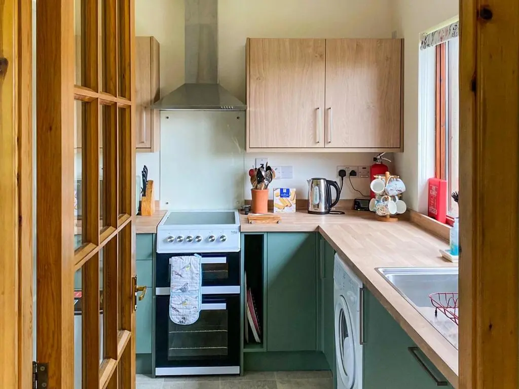 a kitchen with green cabinets and a stove at Kintulloch in Insh