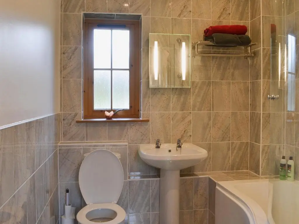 a bathroom with a toilet and a sink and a tub at Turin Nurin Cottage in Tomatin