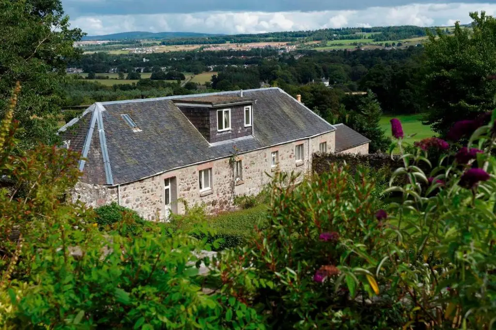 a large stone house with a gray roof at Loch Ness Country House Hotel in Inverness