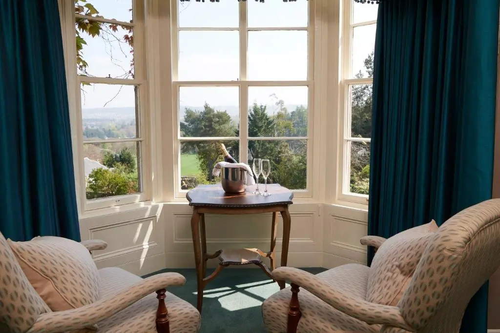 a room with two chairs and a table in front of a window at Loch Ness Country House Hotel in Inverness