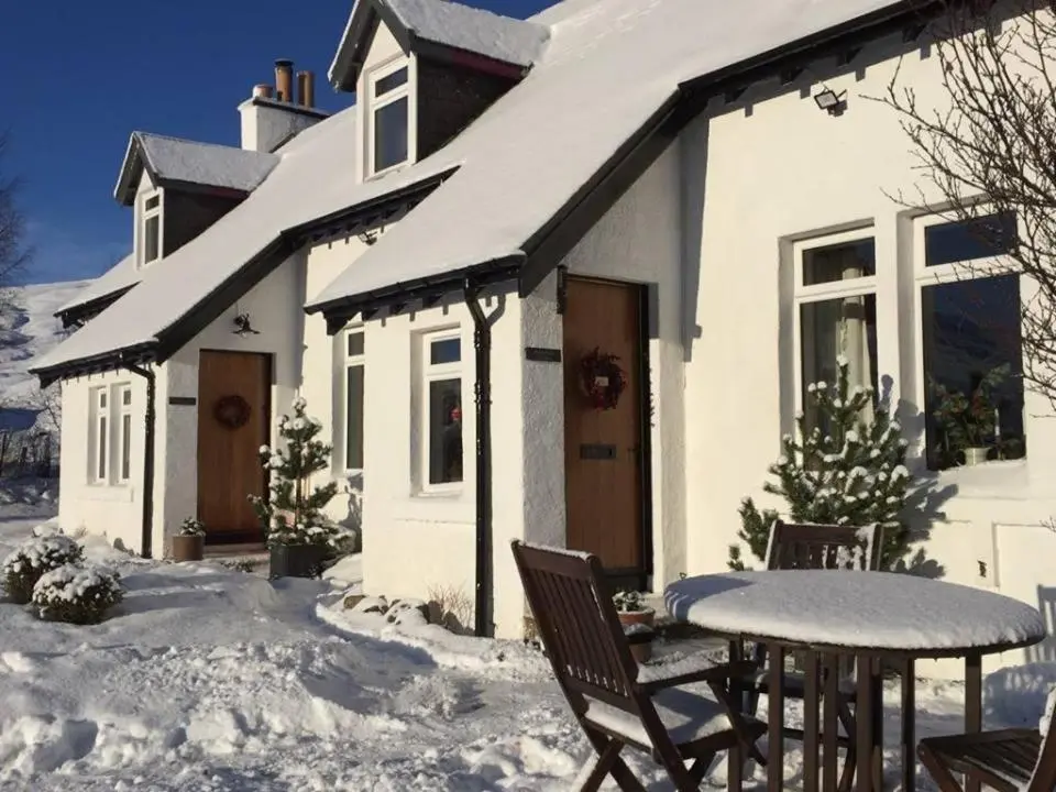 a white house with a table and chairs in the snow at Balsporran Bed And Breakfast in Dalwhinnie