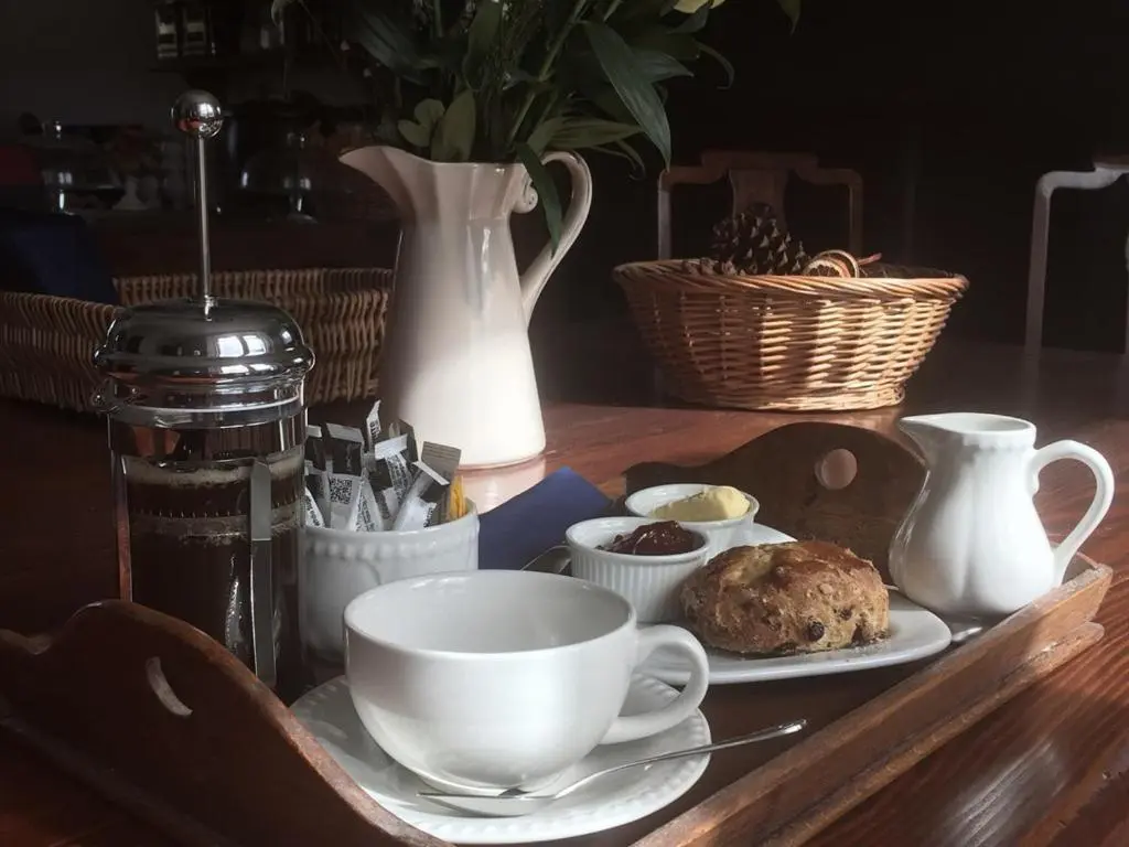 a table with a cup and a plate of food at Balsporran Bed And Breakfast in Dalwhinnie