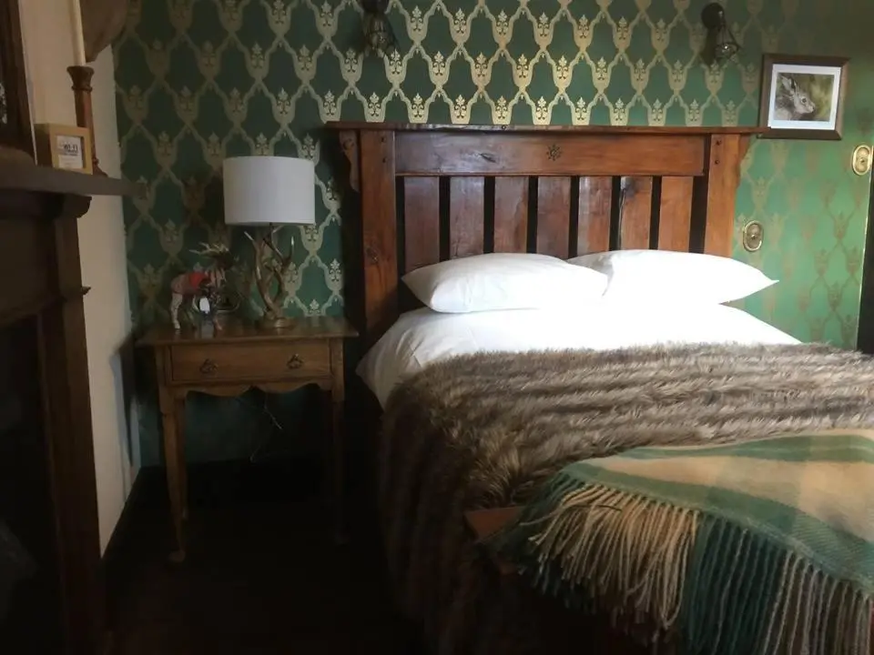 a bedroom with a bed and a table with a lamp at Balsporran Bed And Breakfast in Dalwhinnie