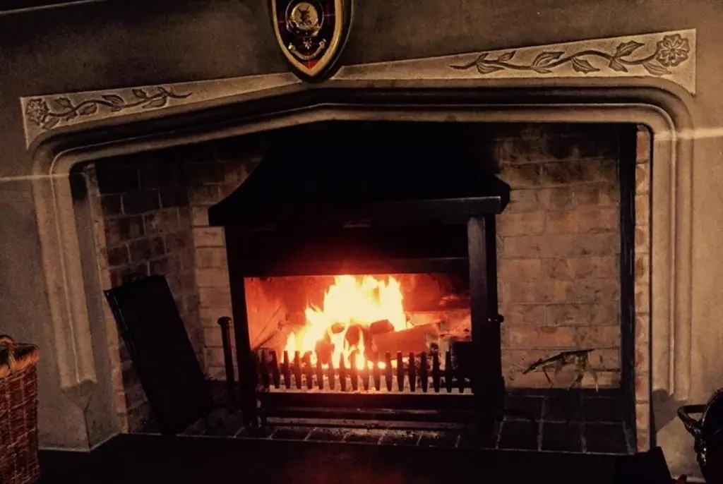a brick fireplace with a fire in it at Highland Bear Lodge & Luxury Bear Huts in Drumnadrochit