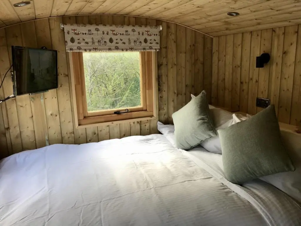a bedroom with a large white bed with a window at Highland Bear Lodge & Luxury Bear Huts in Drumnadrochit