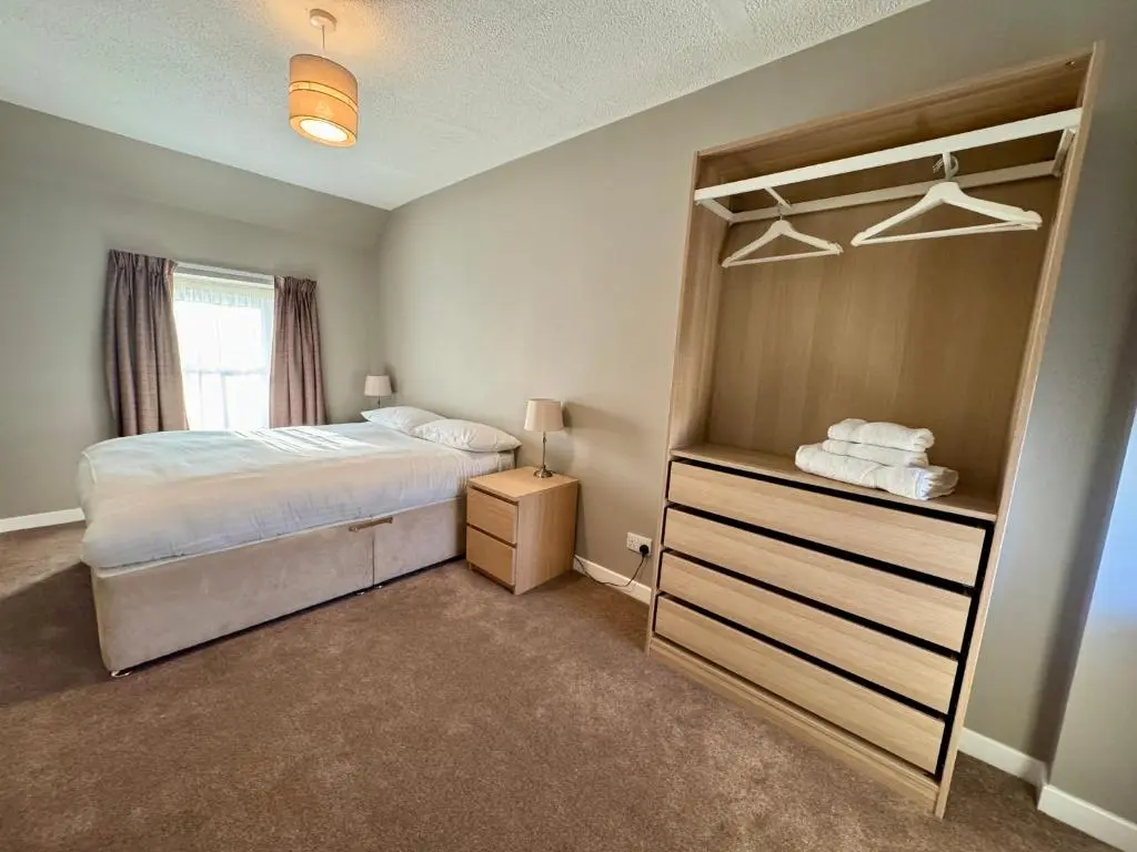 a bedroom with a bed and a dresser in it at The Priory Hotel in Beauly