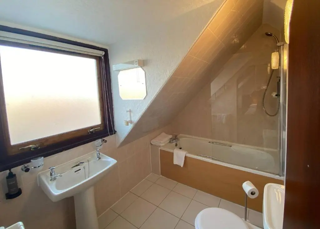 a bathroom with a sink and a toilet and a tub at The Priory Hotel in Beauly