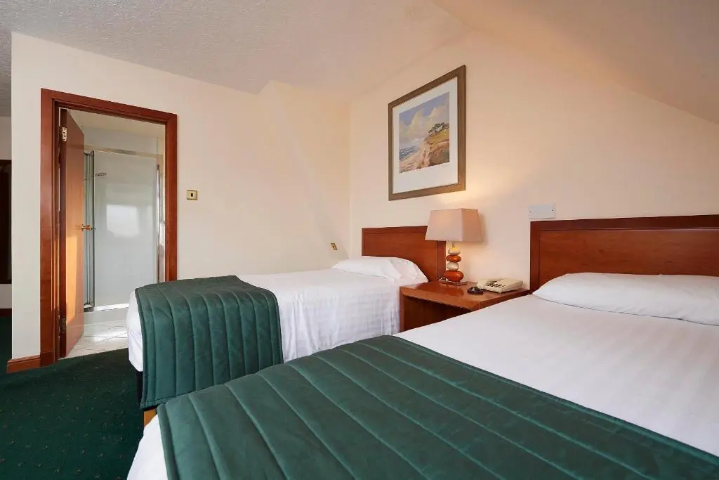 a hotel room with two beds and a mirror at The Priory Hotel in Beauly
