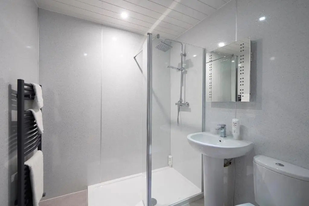 a white bathroom with a shower and a sink at The Priory Hotel in Beauly