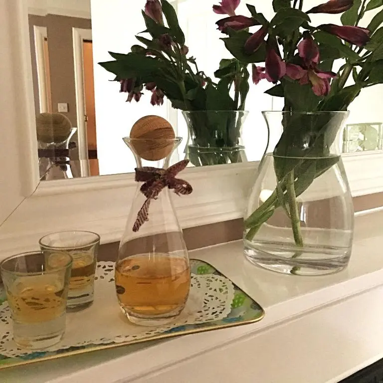 a shelf with two glasses and a vase of flowers at Urrard B&B in Dingwall
