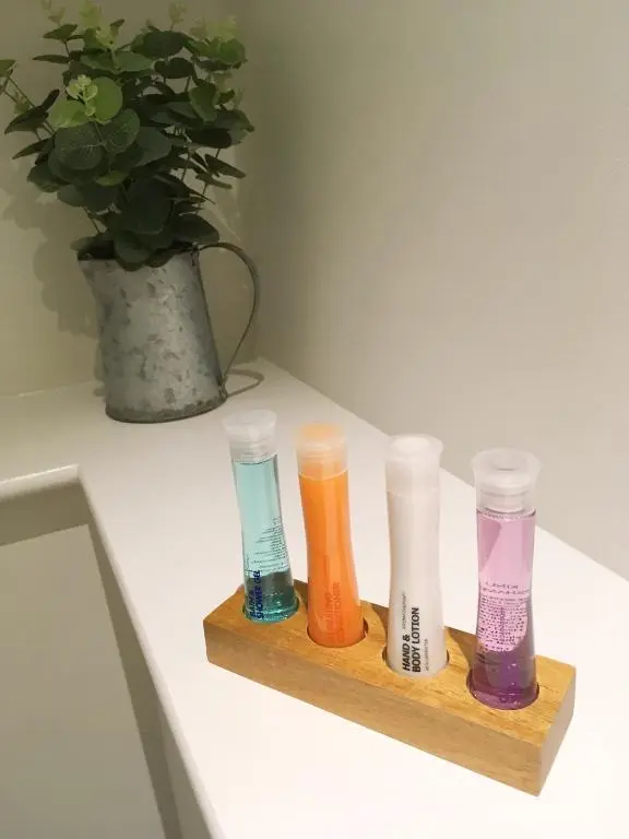 four different colored test tubes sitting on a wooden shelf at Urrard B&B in Dingwall