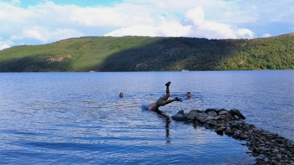 a person is jumping into the water in a lake at Loch Ness Lochside Hostel - Over 16s Only in Invermoriston