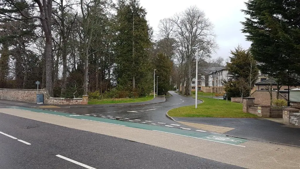 a winding road in a residential neighborhood with trees at Hedgefield House Flat 34 in Inverness