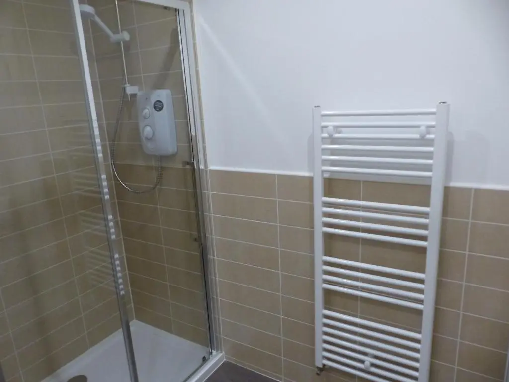 a shower with a glass door in a bathroom at Hedgefield House Flat 34 in Inverness