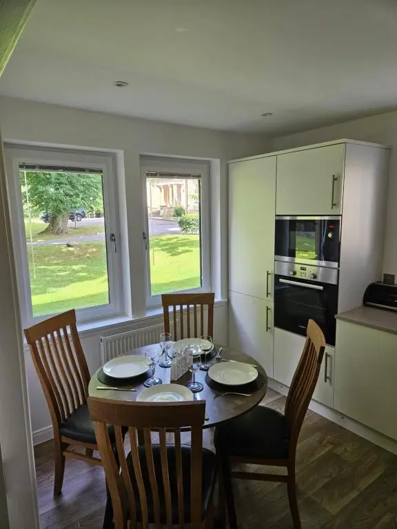 a kitchen with a table and four chairs and a kitchen with a table and chairs at Hedgefield House Flat 34 in Inverness