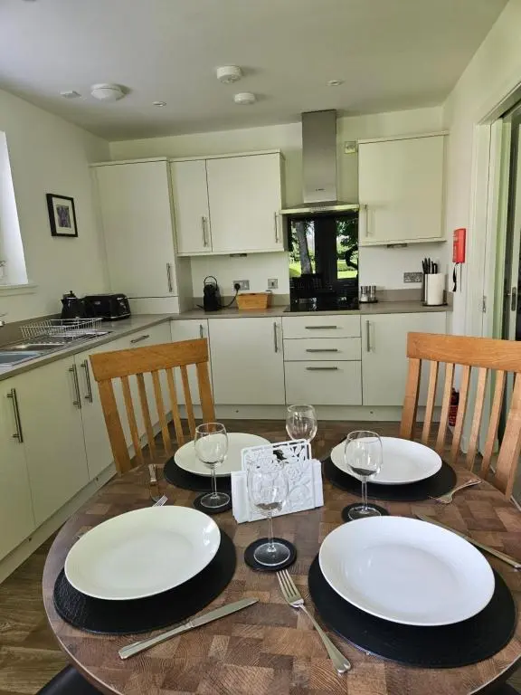 a kitchen with a table with plates and wine glasses at Hedgefield House Flat 34 in Inverness